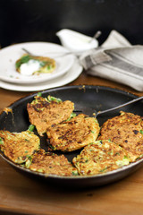 Proper nutrition, vegetarian breakfast gluten free,zucchini courgette pancakes with beans, mint on frying pan with sour greek yogurt, black background, towel, fork, knife on wooden surface
