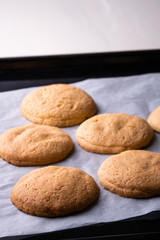 Homemade shortbread cookies on parchment paper in baking tray on wooden white table