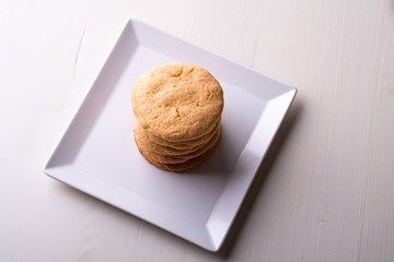 Homemade stack of shortbread cookies on white plate wooden table