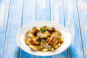 Pasta with chicken and champignon on wooden background