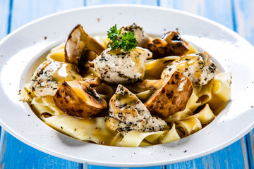 Pasta with chicken and champignon on wooden background