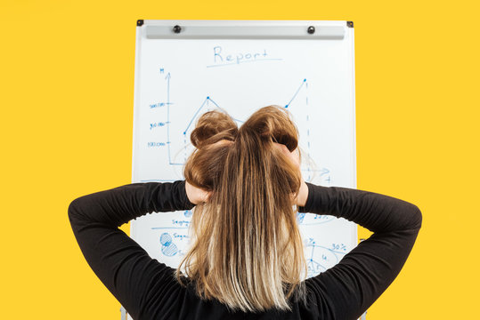 back view of businesswoman standing near white flipchart, holding hand on head