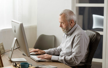 Senior man using his computer at home