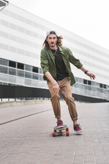 handsome man in casual wear riding on skateboard, looking at camera