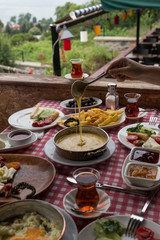 Muhlama , tomato,cheese ,omelette , olive ,jam ,bread in the wooden table at the beautiful view in Istanbul.The enjoying breakfast at the cafe with friends.