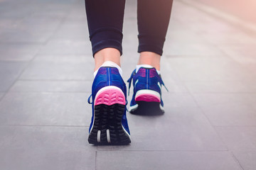 Morning running. Young lady running on a rural road during sunset in blue sneakers with black sole. Healthy lifestyle. Sports training concept