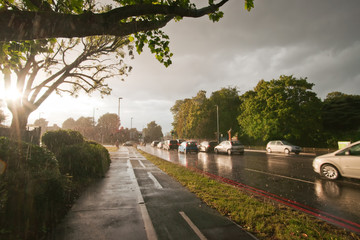 Cars battle through heavy rain and harsh winter sunlight.