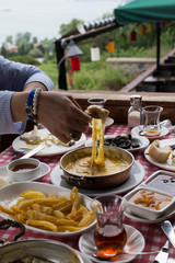 Muhlama , tomato,cheese ,omelette , olive ,jam ,bread in the wooden table at the beautiful view in Istanbul.The enjoying breakfast at the cafe with friends.
