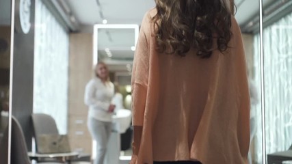 Elegant woman coming to luxury spa salon. Stylish lady holding bag in her hand going through corridor to receptionist for procedure discussion. Slow motion.