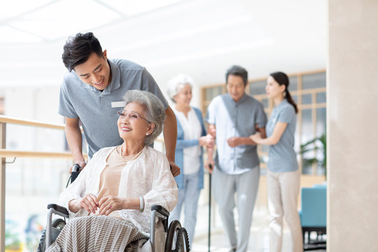 Young nurse assistant taking care of senior woman in wheelchair