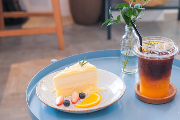 New York cheesecake or classic cheesecake with fresh fruits and ice coffee on white plate,in cafe background