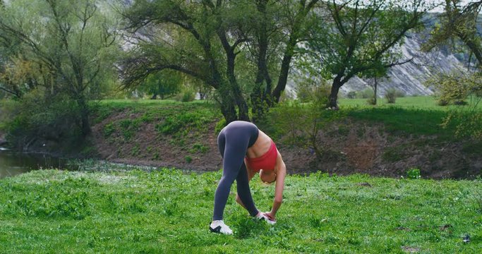 Sport time at nature good looking lady in a sportswear have a great workout morning in amazing place beside a river she stretching body in front of the camera