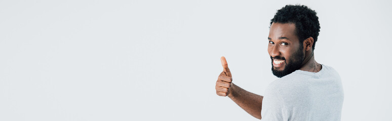 cheerful african american man in grey t-shirt showing thumb up isolated on grey