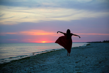Woman on the sea coast on sunset