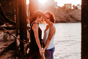 young lesbian couple holding hands at sunset outdoors. Lifestyle and pride concept. love is love - obrazy, fototapety, plakaty