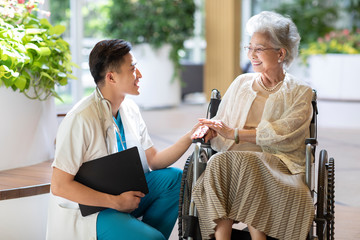 Young doctor talking with patient in nursing home
