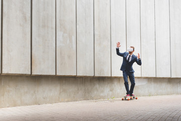 Calm businessman in formal wear and vr headset riding on skateboard, raising hands up