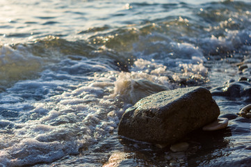 rocky sea shore with pebble beach, waves with foam
