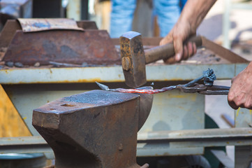 blacksmith performs the forging of hot glowing metal on the anvil