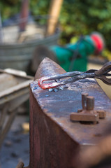 blacksmith performs the forging of hot glowing metal on the anvil