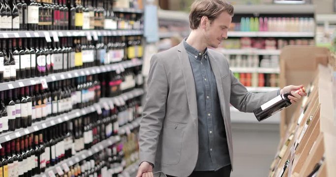 Adult male choosing wine in grocery store