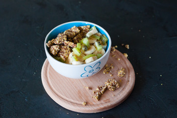 Granola, kiwi, banana and yogurt in a bowl on a wooden stand, dark background. Fitness diet for weight loss and proper nutrition
