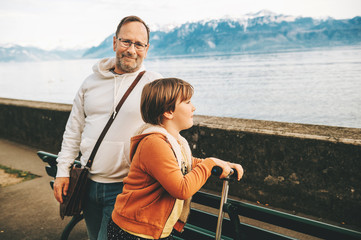 Portrait of handsome man with his little son, promende by lakeside