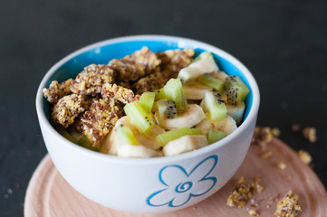 Granola, kiwi, banana and yogurt in a bowl on a wooden stand, dark background. Fitness diet for weight loss and proper nutrition