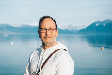 Portrait of handsome man admiring beautiful lake with mountains, wearing white sweatshirt