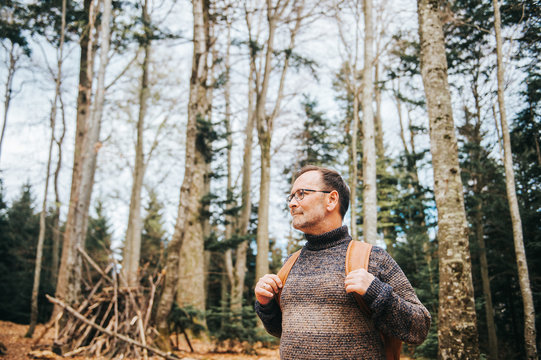 Handsome Middle Age Man Hiking In Forest, Wearing Pullover, Backpack And Glasses