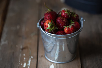 harvest of summer berries. Strawberries in pails on a wooden table. Country style