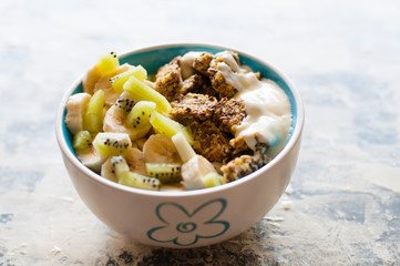 Granola, kiwi, banana and greek yogurt in bowl on a gray concrete background. Fitness diet for weight loss and proper nutrition