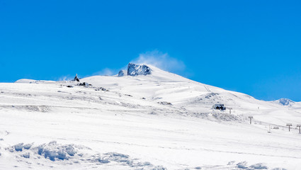El pico Veleta de SIerra Nevada, Granada, nevado en un día soleado con el cielo azul.