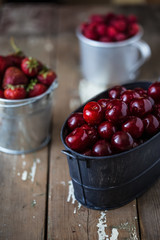 harvest of summer berries. Strawberries, cherries, raspberries in pails on a wooden table. Country style