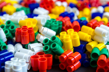 Multicolored plastic building blocks of the designer. Background of plastic colored details building blocks. Parts of bright small spare parts for toys. Close up.