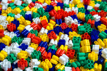 Fototapeta na wymiar Multicolored plastic building blocks of the designer. Background of plastic colored details building blocks. Parts of bright small spare parts for toys. Top view.