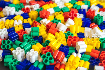 Multicolored plastic building blocks of the designer. Background of plastic colored details building blocks. Parts of bright small spare parts for toys. Close up.