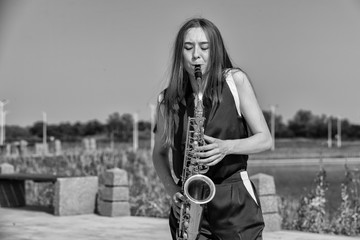 Young beautiful saxophonist with saxophone - outdoor in nature