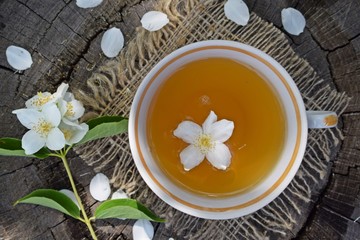 Obraz na płótnie Canvas Jasmine flowers and fresh tea on wooden background and burlap.