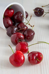 Close-up of cherries in bowl on white wooden background in vertical