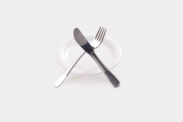 empty plate with knife and fork isolated on white background, clean kitchenware concept