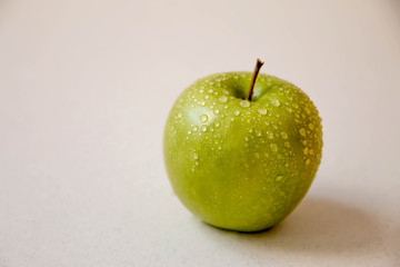 Green apple on a white background, with water droplets