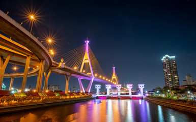 Fototapeta na wymiar Night view of Bhumibol Bridge, also known as Ring road bridge, across Chao Phraya river with colorful light during coronation of King of Thailand on year 2019.