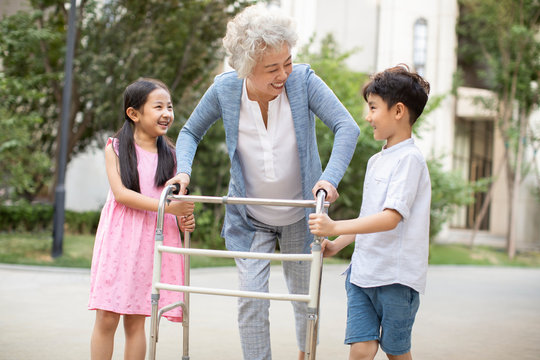 Happy sibling helping grandma walking with walking frame