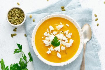 Pumpkin cream soup with feta cheese, autumn homemade food, white background, top view