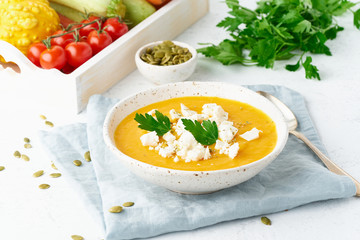 Pumpkin cream soup with feta cheese, autumn homemade food, white background, closeup