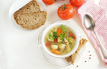 Fresh vegetable soup from potatoes, carrots, cabbage, sweet pepper, brussels sprouts in a bowl with parsley top view