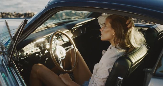 Beautiful woman running her hand through her hair sitting in a classic vintage sports car, elegant woman going on a road trip