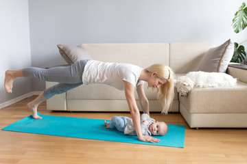 Mother and child with white dog in a bright room with grey walls and wooden floor on blue mat exercising yoga calm fitness white sofa counch in home 