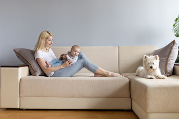 Young mother and child in her hands happy with white westie west highland white terrier dog on a...